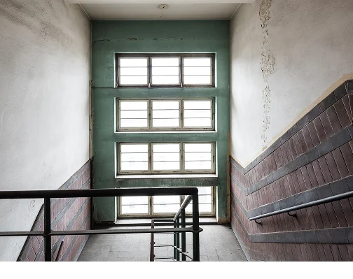 Treppenhaus im Depot mit grün gestrichener Wand und hohem Sprossenfenster