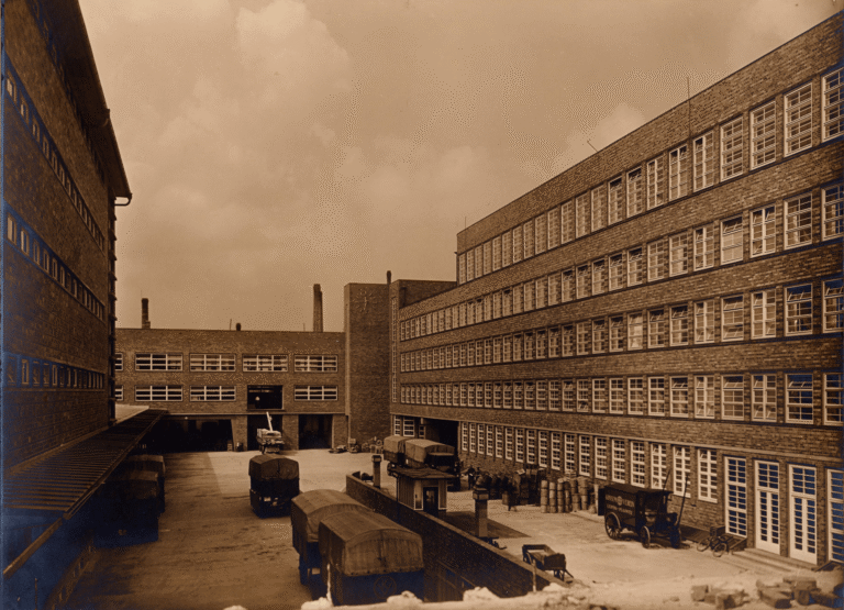 Historische Aufnahme des Innenhofs der Konsumzentrale mit Lieferwagen und Fuhrwerken vor den Laderampen