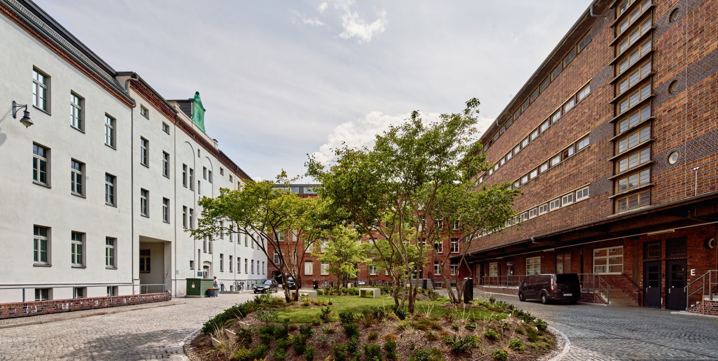 Der Innenhof der Konsumzentrale Leipzig mit begrüntem Rundbeet zwischen Klinker- und Putzfassade